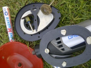 Clockwise from top: The driver mount and the cutting tools, my Dremel and template, the red shell of the ear muffs